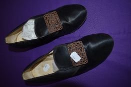 A pair of early 20tch century black shoes with intricate buckles.
