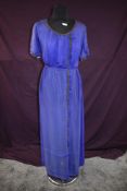 An early 20th century blue silk or silk blend dress having metallic thread edging and glass bead