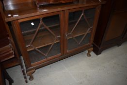 An early 20th Century mahogany low bookcase having astral glazed doors and cabriole legs