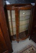 A vintage walnut bow fronted display cabinet, damage to one pane