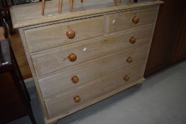 A traditional stripped pine chest of two over three drawers