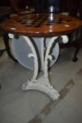 A traditional cast iron table having wooden top with chequer board inlay, diameter approx. 55cm