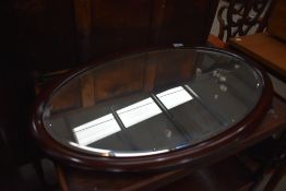 An early 20th Century mahogany framed oval wall mirror, hung in portrait orientation, approx 75 x