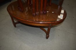 A reproduction mahogany oval coffee table having Adams style legs and glass protector top