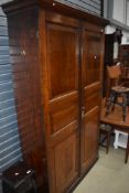 A period pitch pine and oak hall cupboard having pine sides and back oak panelled doors and