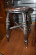 A traditional stool with turned legs and cross support stretcher