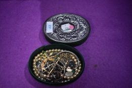 A small green velvet box having embossed white metal decoration to lid containing a small