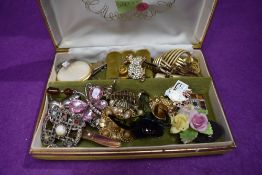 A travel jewellery box containing a small selection of brooches and pin badges including horn,
