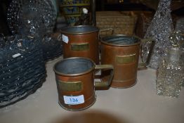 A set of three vintage graduated copper and brass grain measures.