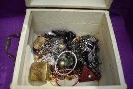 A painted treen jewellery casket containing a selection of metal jewellery including chains, bangles