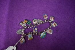 A silver bracelet with padlock clasp having eleven (& two loose) white metal shields stamped silver,
