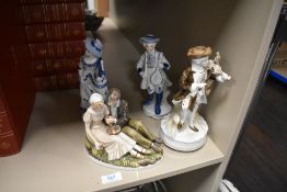 Four ceramic figurines including musicians and couple seated on grass.