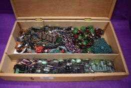 A wooden box containing a selection of beaded necklaces, bracelets and book marks