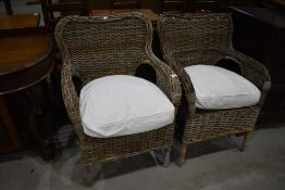 A pair of modern wicker conservatory armchairs
