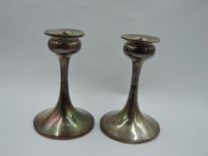 A pair of silver candle sticks having tulip candle holders on tapered stems to weighted circular
