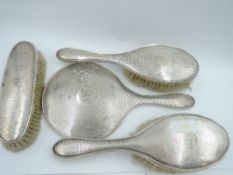 A silver four piece dressing table set having engine turned decoration and monogrammed cartouches,