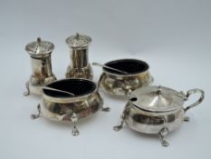 An Edwardian silver five piece cruet set of plain form having blue glass liners and paw feet,