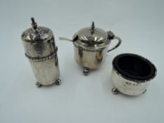 A silver three piece cruet set of plain cylindrical form on trefoil ball feet with blue glass