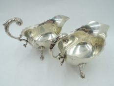 A pair of silver sauce boats having trefoil hoof feet, loop handles and shaped rims, Birmingham