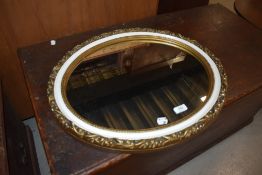 A vintage oval wall mirror, gilt plaster with white trim, width approx 56cm max.