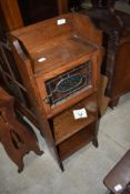 An Arts and Crafts narrow bookshelf with glazed cabinet section to top, having leaded glass door