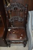 A dark stained hall chair, having ornately carved back rails and solid seat on turned frame