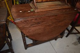 A traditional oak dining table having turned gate legs