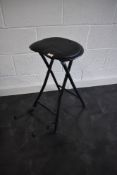 A guitarists folding vinyl stool with integral guitar stand