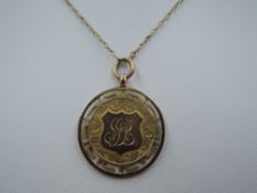 A 9ct gold medalion with engraved decoration and monogram on a yellow metal chain, approx 5.4g