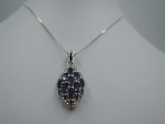 A silver pendant having tanzanite style stones in a decorative mount