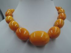 A long string of butterscotch amber beads of oval form with concealed barrel clasp, approx 32' &