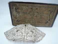 A white metal decorative belt buckle in its original box
