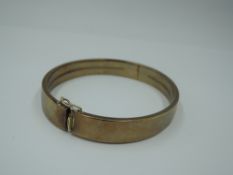 A yellow metal hinged bangle of plain form stamped 333 having concealed clasp and safety clip,