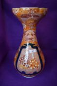 An antique tulip form porcelain vase having iron red ground Japanese decoration of seated samurai