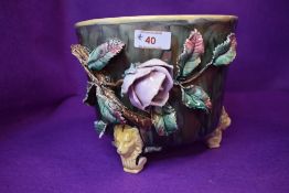 A Majollica style planter having detailed leaf flower and foliage decoration on three footed lion