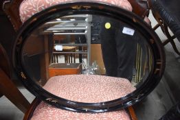 A traditional black laquer work oval wall mirror, width approx. 58cm