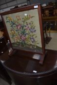 A tradirional mahogany framed woolwork firescreen