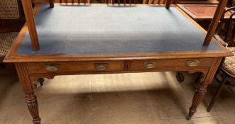 A Victorian oak library table with an inset top above drawers on reeded tapering legs and casters