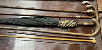 Two silver topped and bamboo walking sticks, together with another walking stick, parasol,