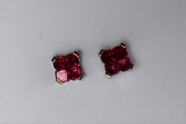 A pair of ruby earrings, each set with four princess cut rubies to a white metal setting and post,