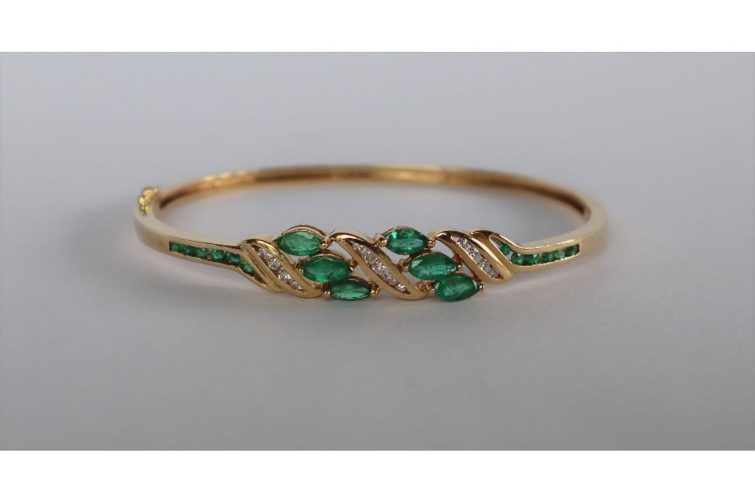 A 14ct yellow gold emerald and diamond set hinged bangle, - Image 1 of 4