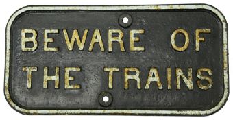 A cast iron notice displaying 'BEWARE OF THE TRAINS'