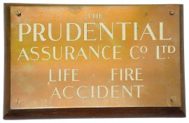 A Prudential Assurance Company copper sign mounted on wooden board,