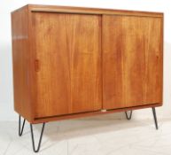 1970’S TEAK WOOD SIDEBOARD WITH SLIDING DOORS RAISED ON HAIRPIN SUPPORTS