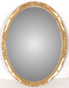 A 20TH CENTURY ANTIQUE STYLE OVAL MIRROR WITH BEVELLED GLASS