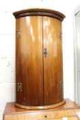 A mahogany bow front hanging corner cupboard.