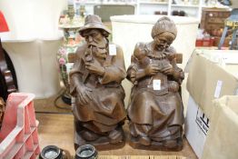 A pair of carved wood figures of a seated man and woman.