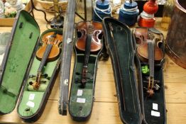 Three violins, complete with cases.