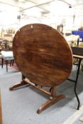 A continental oval walnut tilt top trestle end table.