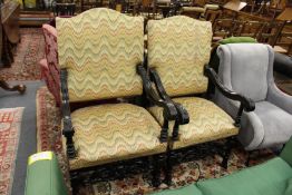 A matched pair of Charles II style armchairs with upholstered backs and seats and ebonised frames.